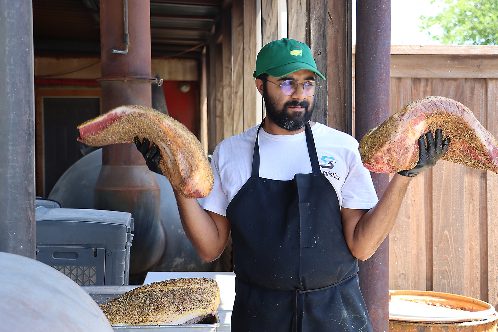 Zain Shafi prepares to put briskets in the smoker at Goldee